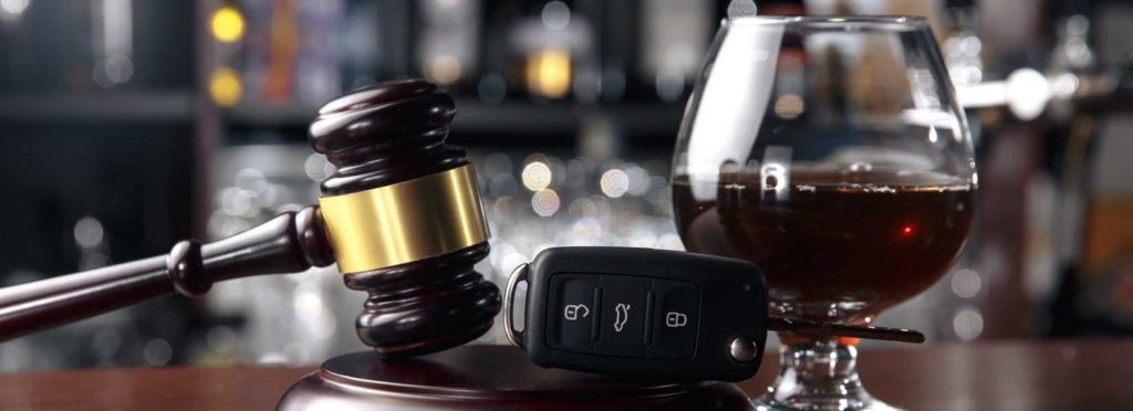 Picture of glass of alcohol next to car keys and gavel